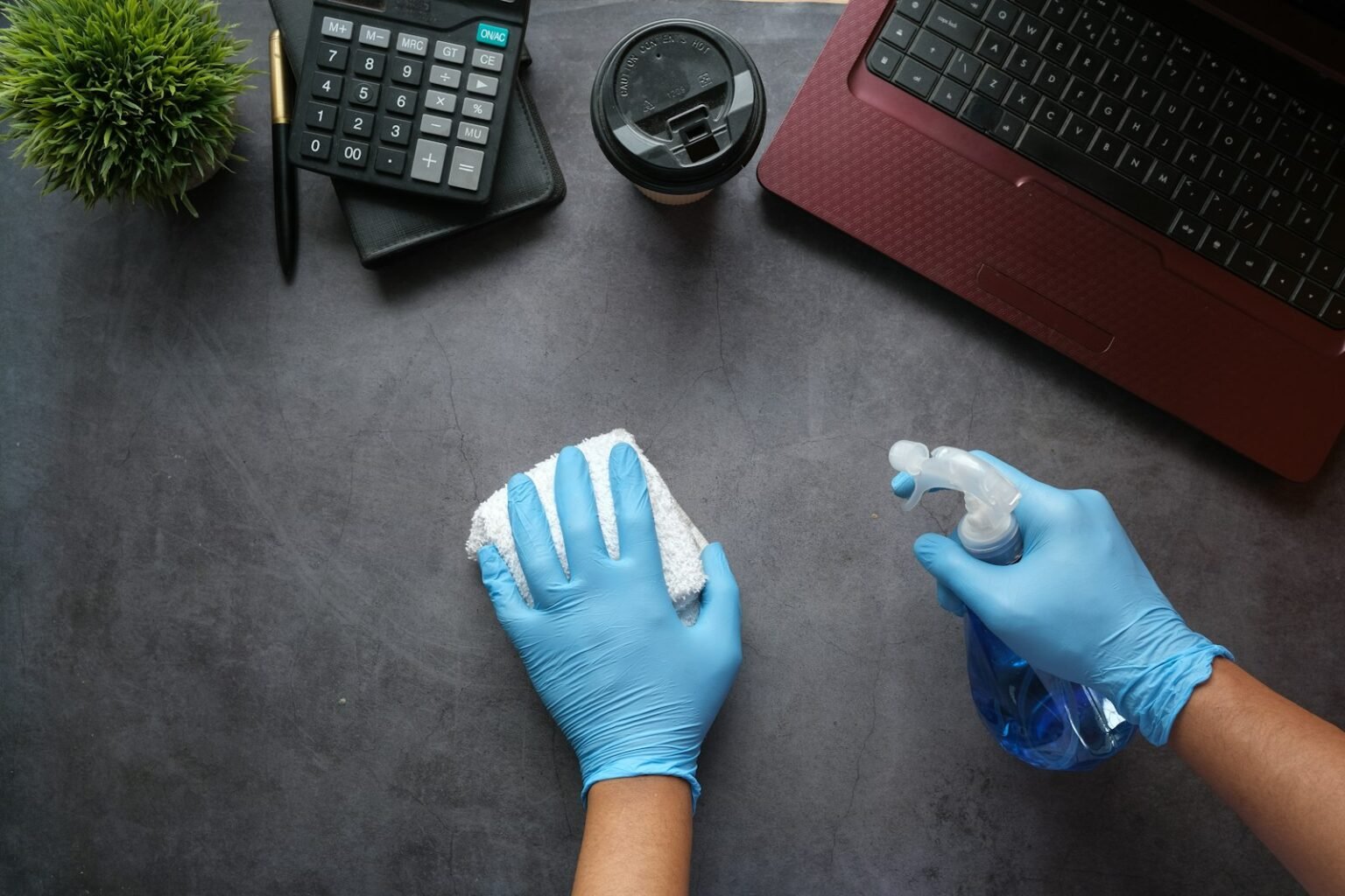 Cleaner wiping a desk with a spray bottle and cloth, illustrating a specific cleaning service worth its own SEO page